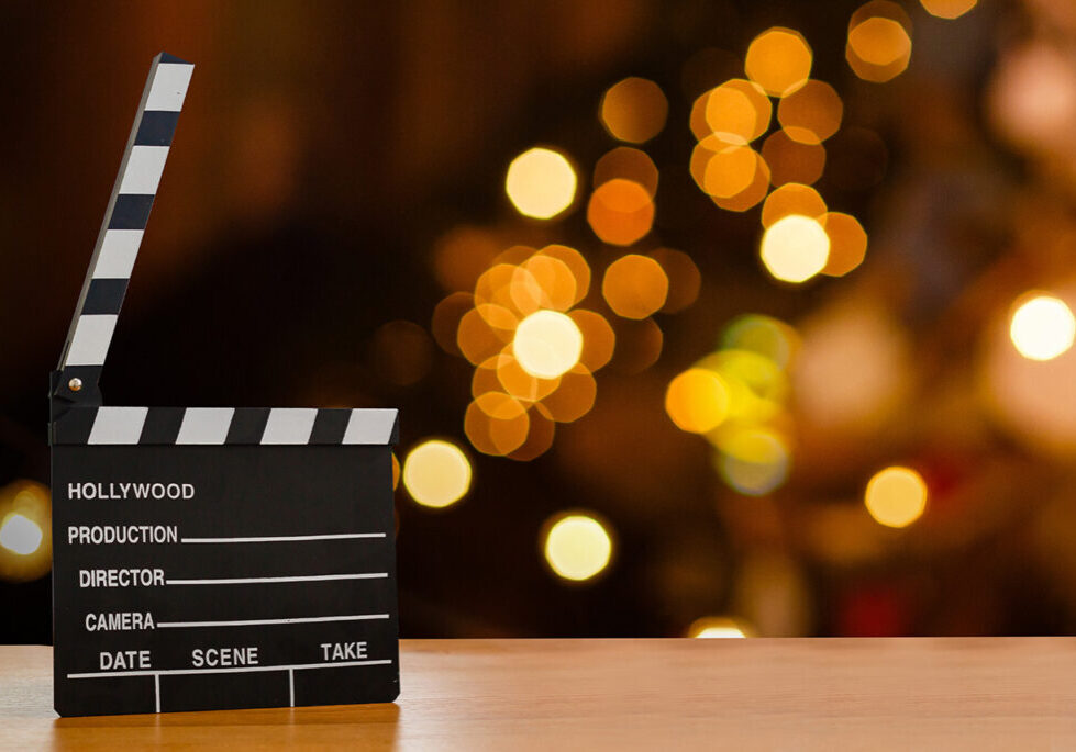 Image of a clapperboard sitting on a table with lights behind it