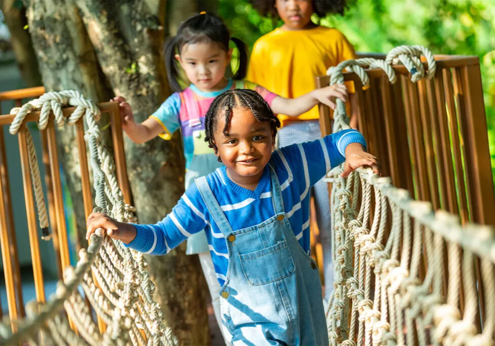 Children walking across a playground rope bridge