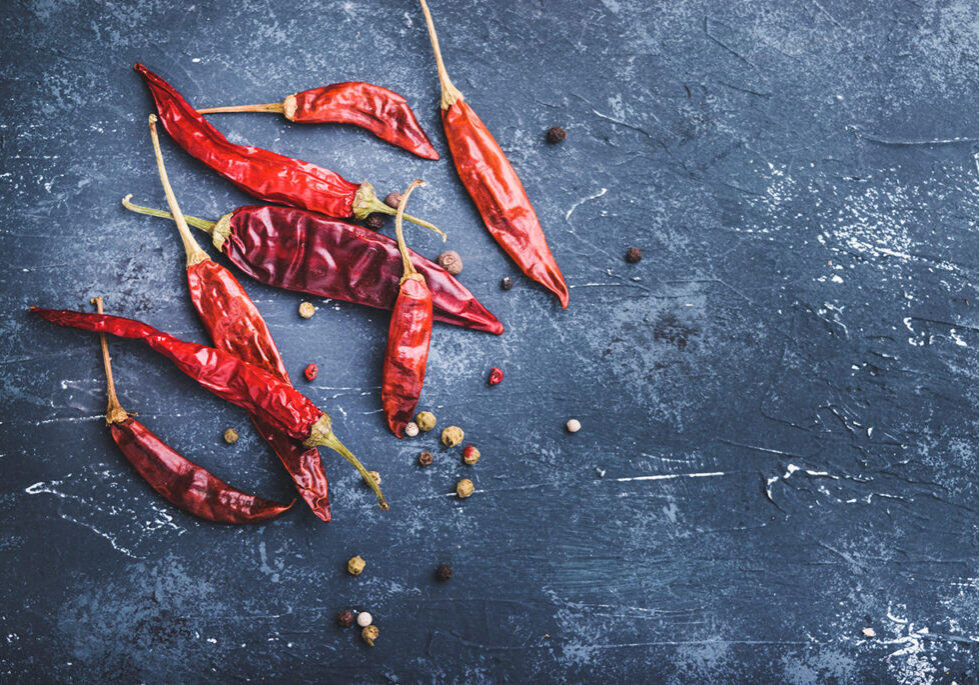 Thai chili peppers laying on a blue stone background